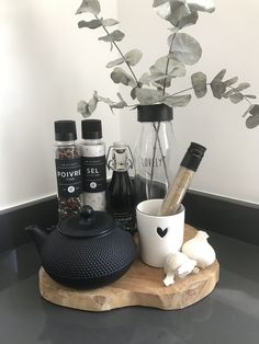 an assortment of spices and condiments sitting on a wooden tray next to a vase