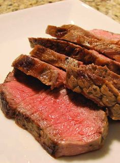 some meat is on a white plate with green peppers