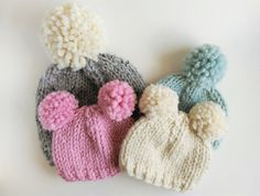 three knitted hats with pom - poms on them