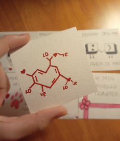 someone is holding up some cards with the names of their chemical symbols on them and hearts