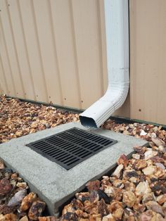 a drain in the ground with rocks around it and a gutter vent on top