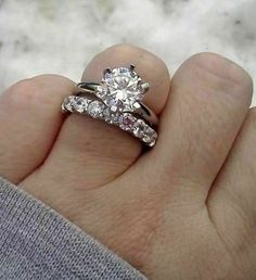 a person's hand holding a diamond ring