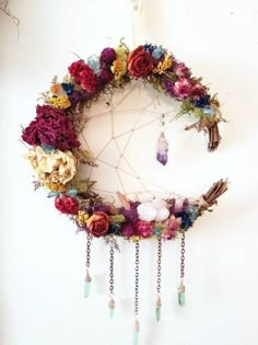 a dream catcher with flowers and feathers hanging from it's side on a wall