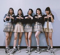 four girls standing next to each other in front of a wall with their hands together