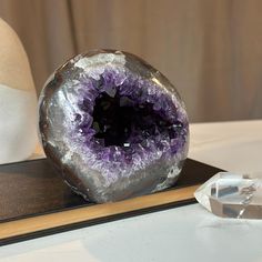 a large amethyst sitting on top of a table next to a crystal rock