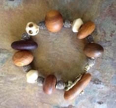 This is a very unusual ethnic bracelet made with wooden and bone beads. It consists of well-balanced different shapes of wood and bone beads with silver spacers.  It has earthy tones, and is bold and very unique. It is an ethnic wood bracelet that is interesting and special to wear. It is the perfect neutral bracelet to add to your bracelet collection. It has a wooden button closure and a loop that is composed of small African brass tubes. 9 inches long Bohemian Adjustable Wooden Beaded Bracelets, Adjustable Wooden Bohemian Beaded Bracelets, Bohemian Wooden Bead Bracelets, Bohemian Wood Beaded Bracelets, Bohemian Wood Bracelet Jewelry, Artisan Brown Wooden Beaded Bracelets, Earthy Brown Wooden Bead Bracelets, Neutral Bracelet, Earthy Brown Multi-strand Jewelry