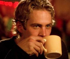 a close up of a person holding a coffee cup with his hand near his face