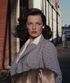 a woman in a checkered coat is holding a purse