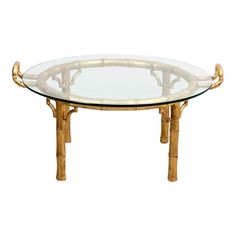 a glass table with gold bamboo legs and a round glass top on an isolated white background