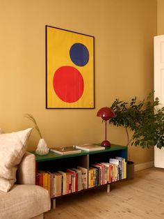 a living room with a couch, coffee table and bookshelf in front of a painting on the wall