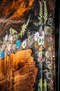 an artistic piece of wood with flowers and leaves painted on the side, along with other pieces of wood