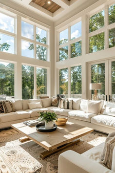 a living room filled with lots of white furniture and large windows above the couches