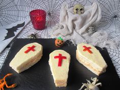 three pieces of cake with crosses on them sitting on a black plate next to a candle