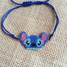 a beaded bracelet with a cat face on it's side and blue cord