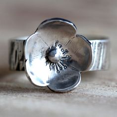 This statement ring is made from sterling silver and is decorated with a handmade sterling silver flower. The band is 6mm wide, 1.2mm thick and is textured with hammered ridges. The flower is approximately 14mm wide but as they are handmade, each will be slightly different. It is made from sterling silver but has a fine silver ball in the middle. The ring is oxidised to better show the texture of both the band and flower. It is made from 100% recycled sterling silver. The ring in the photos has Jewelry Silver Rings, Gold Infinity Ring, Silver Rings For Women, Interlocking Ring, Silver Flower Ring, Bohemian Ring, Ring Flower, Vintage Style Rings, Black Diamond Ring Engagement