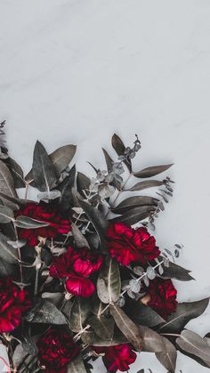 a bouquet of red flowers sitting on top of a white table