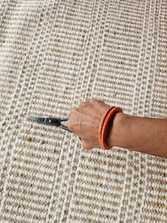 a hand holding a pair of scissors on top of a rug