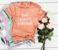 Grit Grace & Gratitude... don't we all need a little bit of all of that. This T-shirt is so cute. It's a perfect T-shirt for a gift or yourself.... or both. You'll love the softness of the T-shirt . Multiple color options. Bella brand T-shirt . White text . Fits true to size . Retail cut. Soft T-shirt This is a unisex cut T-shirt. But I promise you it fits everyone perfect! Let us know if you would rather a women cut. We can send you a size chart for a custom option. Size chart listed. Tshir Grit Grace Gratitude, Gratitude Shirt, Grit Grace, Boutique Designs, Happy Tees, Grit And Grace, Cut T Shirt, Blue Crew, Green Hoodie