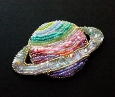 a multicolored beaded brooch sitting on top of a black surface