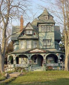 an old victorian style house with many windows and porches on the second floor, surrounded by trees