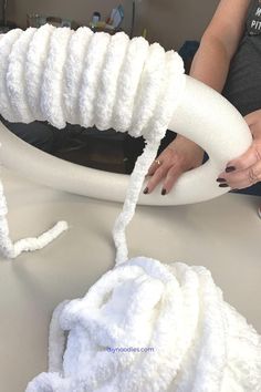 a woman is working on an object with white yarn