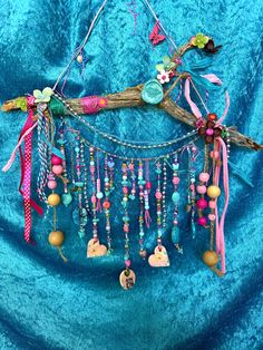 a piece of driftwood with beads and other things hanging from it on a blue velvet background