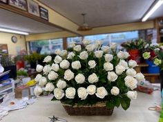 a basket filled with white roses sitting on top of a table next to other flowers