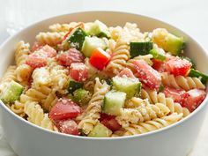 a white bowl filled with pasta salad on top of a table next to a napkin