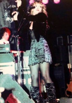 a woman standing on top of a stage with a microphone in her hand and another person behind her