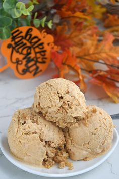 three scoops of ice cream sit on a white plate next to some fall leaves