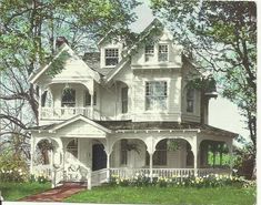 an old victorian house is painted white and has flowers in the front yard, along with some trees