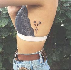 the back of a woman's stomach with a small flower tattoo on her left side