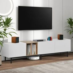 a living room with white furniture and a large flat screen tv mounted on the wall