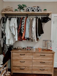 a wooden dresser sitting next to a closet filled with clothes