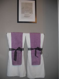 two purple and white towels hanging on the wall