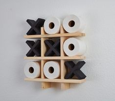 several rolls of toilet paper are stacked up on a wooden shelf with two black crosses