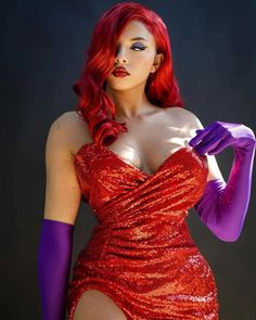 a woman in a red dress and purple gloves posing for the camera with her hands on her hips