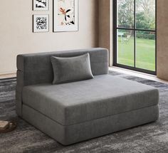 a large gray couch sitting in front of a window next to a wall with pictures on it