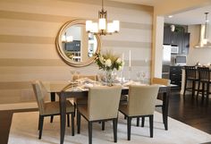 a dining room table and chairs in front of a wall with vertical stripes on it