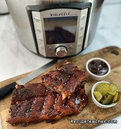 ribs and pickles on a cutting board in front of an instant pot