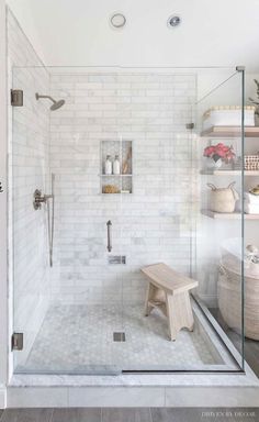 a walk in shower sitting next to a white tiled wall with shelves on the side