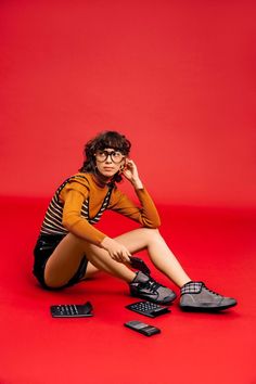 a woman sitting on the ground with her legs crossed and shoes in front of her