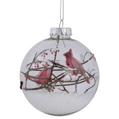 a glass ball ornament with two birds on branches in snow and red berries