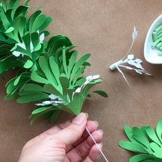 someone is making some paper flowers out of green leaves