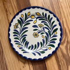 a white and blue plate sitting on top of a wooden floor next to a wall