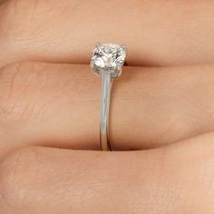 a woman's hand with a diamond ring on top of her finger, showing the center stone