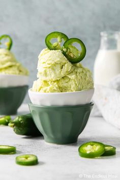 two bowls filled with green jello and sliced jalapenos on the side