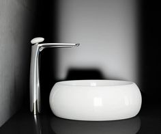 a white bowl sitting on top of a black counter next to a faucet