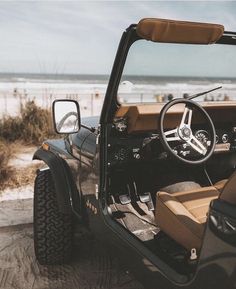 a jeep parked on the beach with its door open and steering wheel still in position