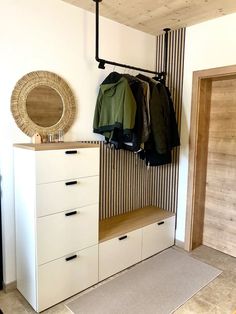 a coat rack with two coats hanging on it next to a white dresser and mirror